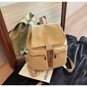 Vista macro de mochila de lona beige con cierre de cordón y cremalleras metálicas