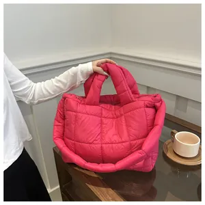 Detail of fuchsia quilted down tote bag with nylon fabric texture and zipper closure