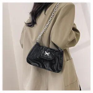 Detailed view of black marble pattern bag with silver butterfly buckle and chain strap