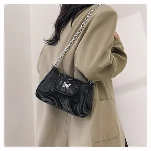 Detail of black underarm bag with fluid marble pattern and silver butterfly buckle