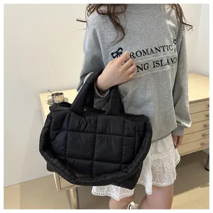 Macro detail of black quilted puffy tote bag showing high-quality stitching and texture