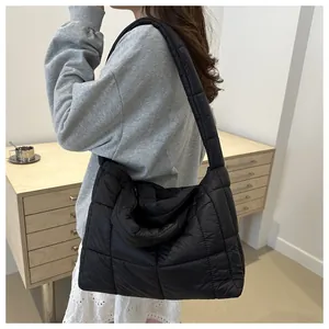 Macro view of black quilted down tote bag with wide shoulder strap and soft nylon fabric