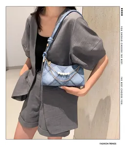 Détail du sac à bandoulière en denim bleu clair avec perles et chaîne dorée élégante