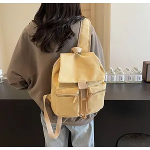 Detalle de la mochila de lona amarillo mostaza con cordón ajustable y bolsillos delanteros