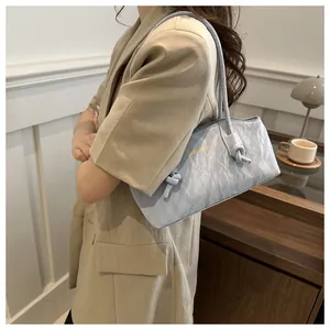 Detail of light blue shoulder bag with pleated texture and golden brand logo