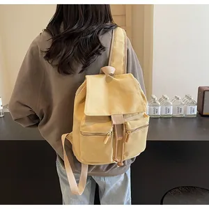 Detalle de la mochila tipo cubo de lona amarilla con cordón y dos bolsillos delanteros de cremallera