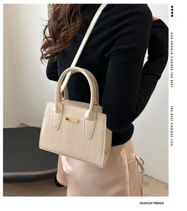 Detail view of beige stone pattern small handbag with gold buckle and slim strap