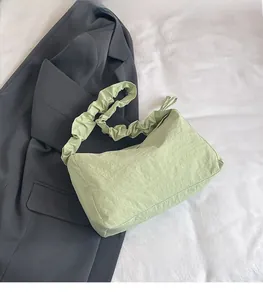 Detail der hellgrünen Schultertasche mit Faltenriemen und weicher Stofftextur auf Blazer