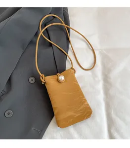 Dettaglio borsa porta cellulare giallo senape testurizzata con perla e tracolla sottile