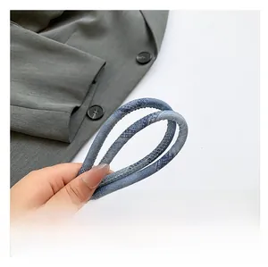 Détail macro de la bandoulière en denim bleu avec boucle en métal doré de qualité