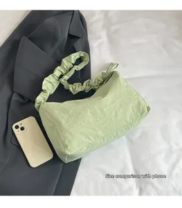 Detailansicht der mintgrünen Rafftasche neben einem Handy als Größenvergleich