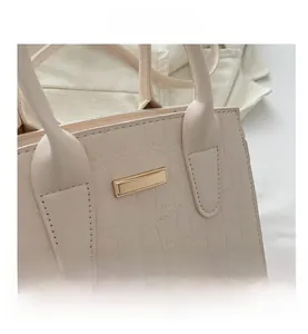 Close-up of stone-textured cream tote bag featuring golden rectangular hardware detail