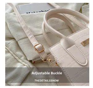 Detail of adjustable golden metal buckle and croc-embossed leather strap on beige bag