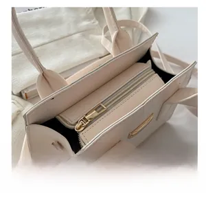 Close-up of white crocodile texture handbag featuring smooth gold zipper and black lining