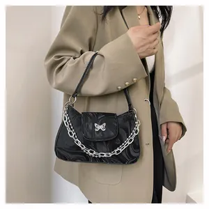 Detail of vintage black bag with marble texture, silver butterfly and metal chain