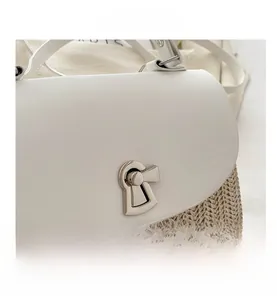 Detail of straw handbag with white leather flap and silver metal turn-lock closure