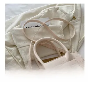 Macro view of beige faux crocodile leather shoulder bag with gold metal buckle detail