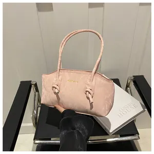 Detail of pink pleated fabric handbag with stylish knotted handle and brand logo