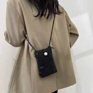 Mini borsa a tracolla nera con fibbia di perle e trama a pieghe indossata dal modello