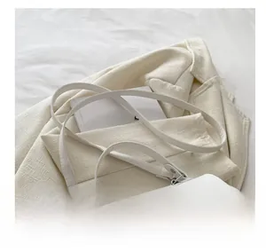 Close-up of elegant white leather handbag with silver lock and adjustable shoulder strap