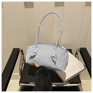 Detail of light blue wrinkled fabric shoulder bag with gold logo and knotted strap