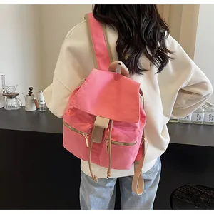 Vista trasera de una mochila tipo cubo de lona rosa con correas caqui en una modelo