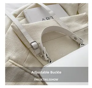 Detail of silver adjustable buckle and white leather strap on a summer straw handbag