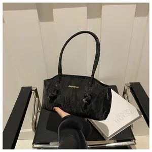 Close-up of black pleated texture shoulder bag with gold logo and elegant knot detail