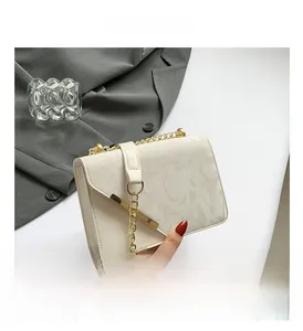 Close-up of cream square bag with letter texture and gold metal edge detail