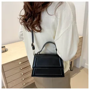 Rear view of a model wearing the minimalist black leather crossbody square handbag