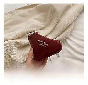 Détail macro du mini sac cœur bordeaux en cuir verni brillant avec bandoulière chaîne