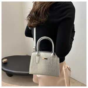 Silver crocodile texture handbag shown with long shoulder strap in a modern indoor setting