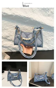 Détail du sac hobo en denim bleu avec surpiqûres matelassées et chaîne en perles