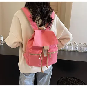 Mochila de lona rosa con cierre de cordón y correas marrones mostrada en una modelo