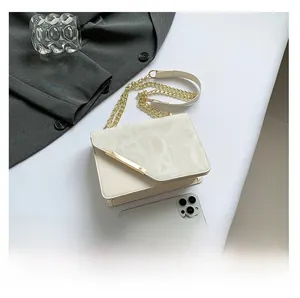 Detail view of cream mini square crossbody bag with embossed texture and metal trim accents