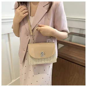 Detail of woven straw handbag featuring a beige leather top cover and silver metal twist lock