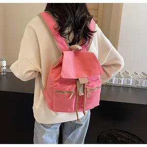 Detalle de mochila tipo cubo en lona rosa con correas caqui y dos bolsillos con cremallera