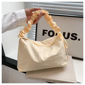Detailansicht des cremefarbenen Faltenstils und des strukturierten Stoffes der kleinen Tasche