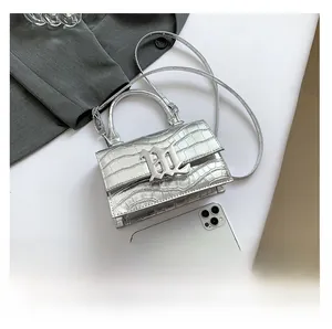 Detail der silbernen Mini-Handtasche mit Krokomuster im Größenvergleich zum Smartphone