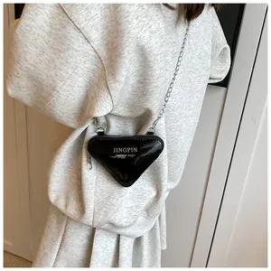 Gros plan sur le mini sac triangulaire noir brillant avec chaîne en argent et fermeture