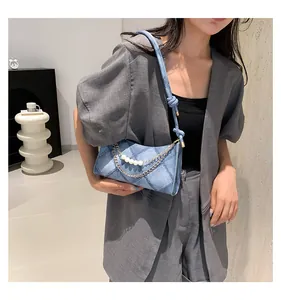 Détail du sac sous le bras en denim bleu clair avec chaîne de perles et surpiqûres portées