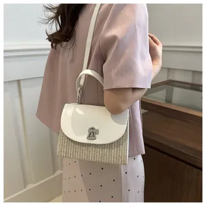 Detail of summer straw crossbody bag with white leather flap and vintage metal lock