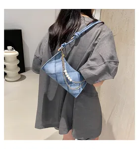 Détail du sac à bandoulière en denim bleu clair avec perles blanches et chaîne dorée