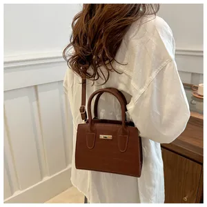 Brown crocodile embossed handbag showing size and style on model in a cozy home setting