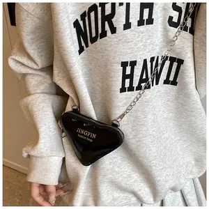 Détail d'un mini sac triangulaire noir brillant avec fine chaîne argentée et logo
