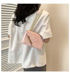 Detail of light pink shoulder bag with geometric embossed pattern and gold chain strap