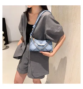 Détail du sac en jean matelassé bleu clair avec perles blanches et chaîne dorée