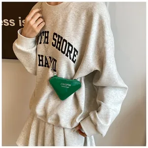 Gros plan détaillé d'un mini sac triangle vert vif avec chaîne en argent et logo