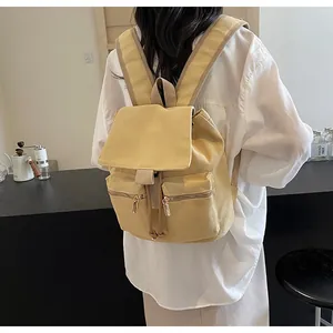 Detalle de mochila tipo cubo de lona amarilla con cordón y solapa en una modelo femenina