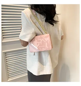 Detail view of pink crossbody bag with gold chain strap and geometric textured flap